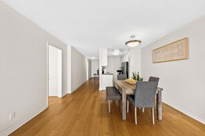 Eine moderne Küche mit weißen Schränken, einem Holztisch und einer Pendelleuchte.