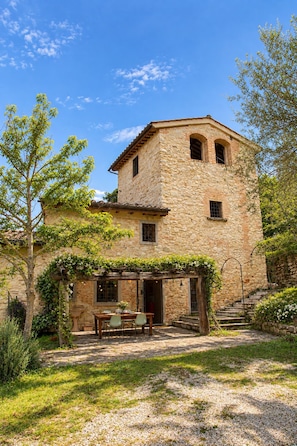 Un edificio de piedra con un patio, una mesa y sillas.