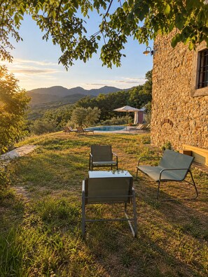 Un edificio de piedra con piscina, mobiliario exterior y vistas al campo.
