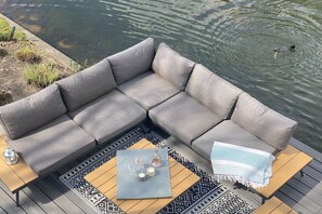 Ein graues Ecksofa mit einem gemusterten Teppich und einem kleinen Tisch mit Gläsern und Kerzen.