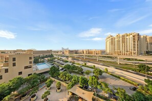 A high-rise residential building with multiple balconies, a parking area with several cars, and a clear sky. - StayShort - Superb 3BR in Palm Jumeirah With Unmatched Views for 5! (Palm Jumeirah)