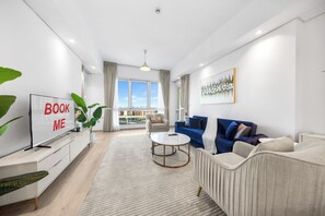 A modern living room with a sofa, a coffee table, and a TV on a stand. - StayShort - Superb 3BR in Palm Jumeirah With Unmatched Views for 5! (Palm Jumeirah)