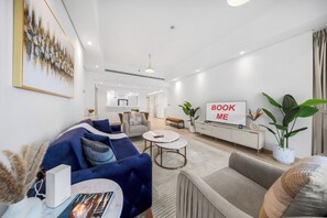 En moderne stue med sofa, lænestol og sofabord. Et skilt på væggen siger 'BOOK ME'.