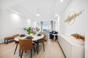 A modern dining area with a round table, chairs, and a view of the city. - StayShort - Superb 3BR in Palm Jumeirah With Unmatched Views for 5! (Palm Jumeirah)