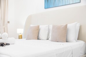 Et hotelværelse med en pænt redt seng, en lampe og et billede på væggen.