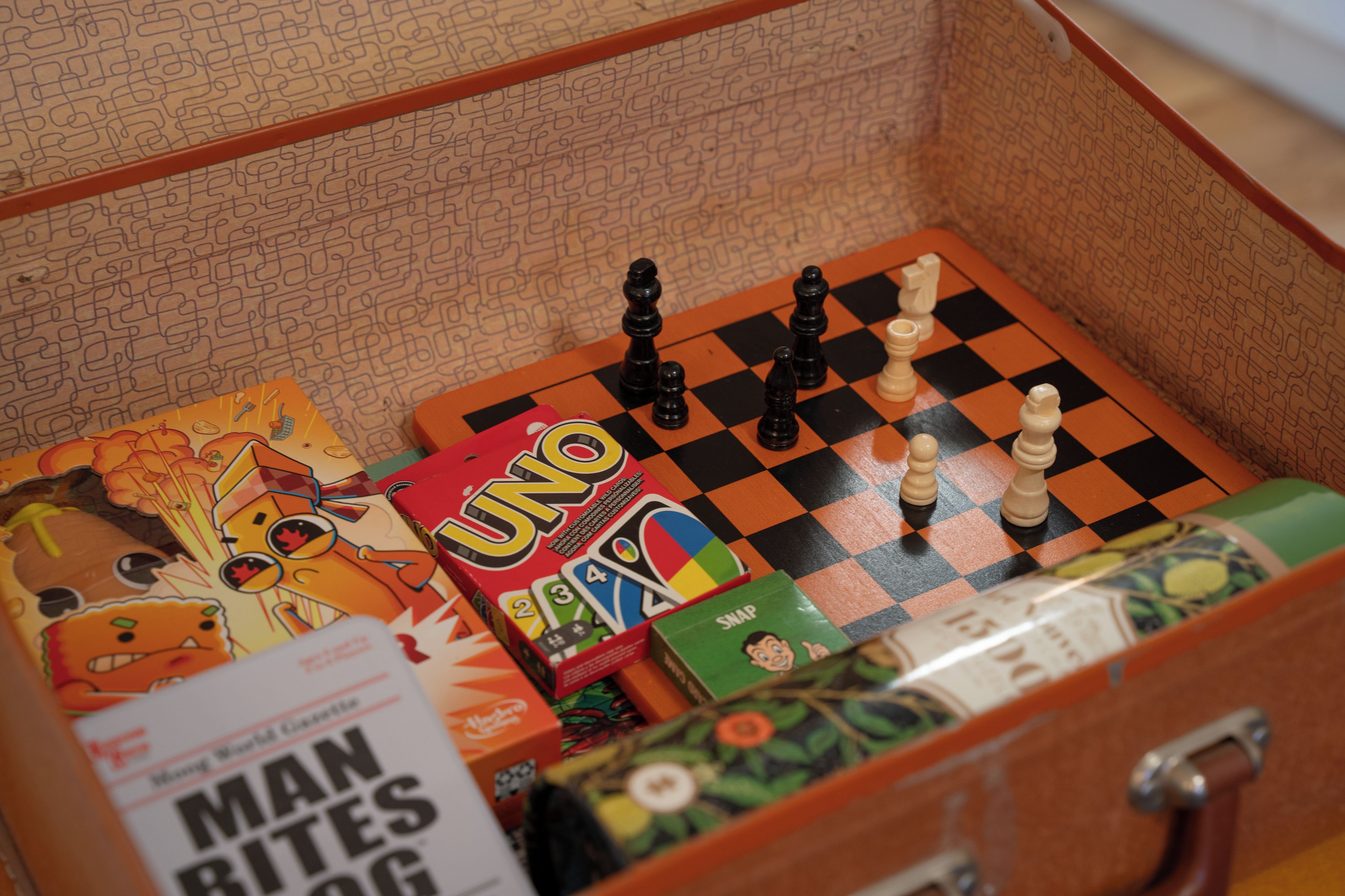 A chessboard with pieces, a 'UNO' game box, and a 'Man Bites Dog' book.