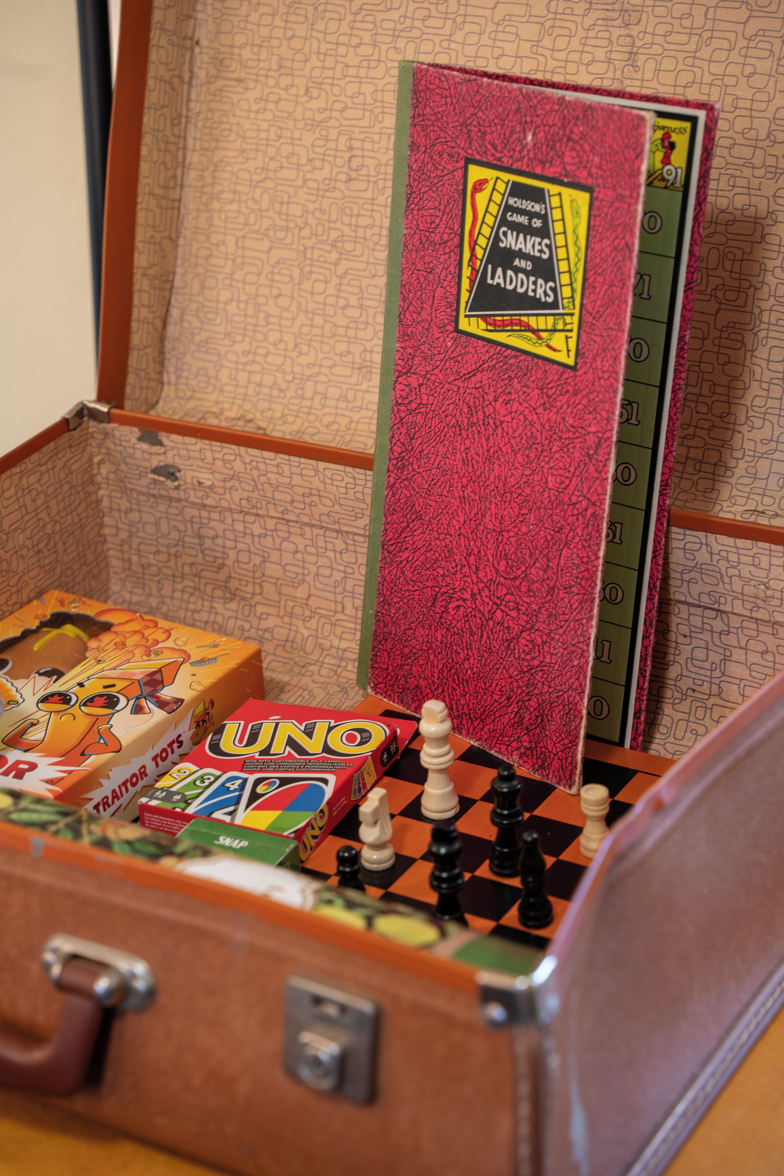 Una maleta antigua con juegos de mesa y un juego de la Escalera.