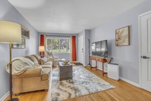 Een woonkamer met een bank, een salontafel, een televisie en een radiator.
