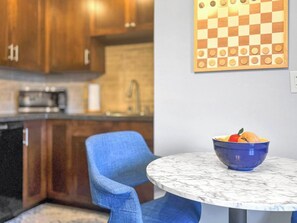 A kitchen with wooden cabinets, a sink, and a marble table with a blue bowl containing fruit. - Seagulls Nest | Steps 2 Lake! Massage Chair! (Sheboygan)