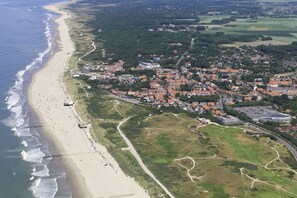 An aerial view of a coastal town with a beach, residential areas, and green fields. - Residence Ruimzicht 35 (Domburg)