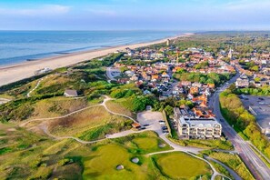 An aerial view of a coastal town with a beach, residential areas, and a prominent church. - Residence Ruimzicht 35 (Domburg)