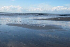 Een strand met een uitgestrekte zandvlakte en rustige golven.