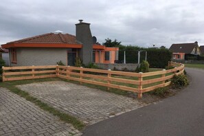 Ein Wohnhaus mit gepflasterter Auffahrt, Holzzaun und einer Ziegelhaus mit Ziegeldach.