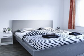 Un dormitori modern amb un llit, fallegueres i una finestra amb cortines.