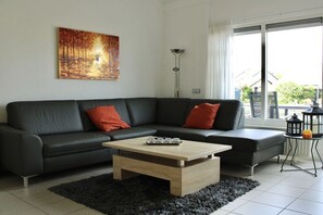 Ein modernes Wohnzimmer mit einem schwarzen Ledersofa, einem Holztisch und einem Gemälde an der Wand.