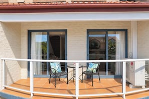 Ein Balkon mit zwei Stühlen, einem Tisch und einer Glasschiebetür, mit Fliesenboden.