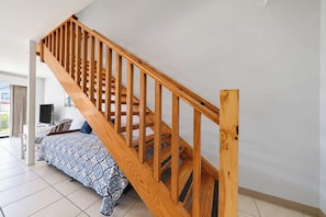 Ein Zimmer mit einer Holztreppe, einem Bett mit gemusterten Betttextilien und einem Fernseher in der Ecke.