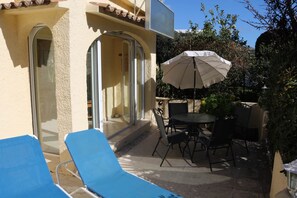 A patio with a table and chairs, a blue lounge chair, and a white umbrella. - Don Lotario – Bungalow with communal pool (Moraira)