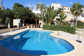 A swimming pool with a curved edge, surrounded by a tiled deck and a pergola. - Don Lotario – Bungalow with communal pool (Moraira)