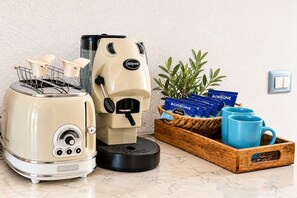 Een keuken met een broodrooster, een koffiezetapparaat en een dienblad met koffiepads en een mok.