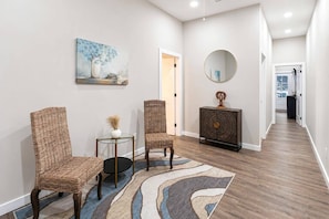 A hallway with two wicker chairs, a small round table, a decorative console, and a painting on the wall. - Luxury for 2 Traveling for Business (Atlanta,)