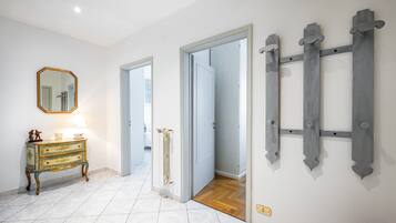 A hallway with a white tiled floor, a wooden door, and a wall-mounted radiator.