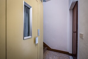 A hallway with a yellow door, a window, and a wooden door. - Rondinella (Florence)