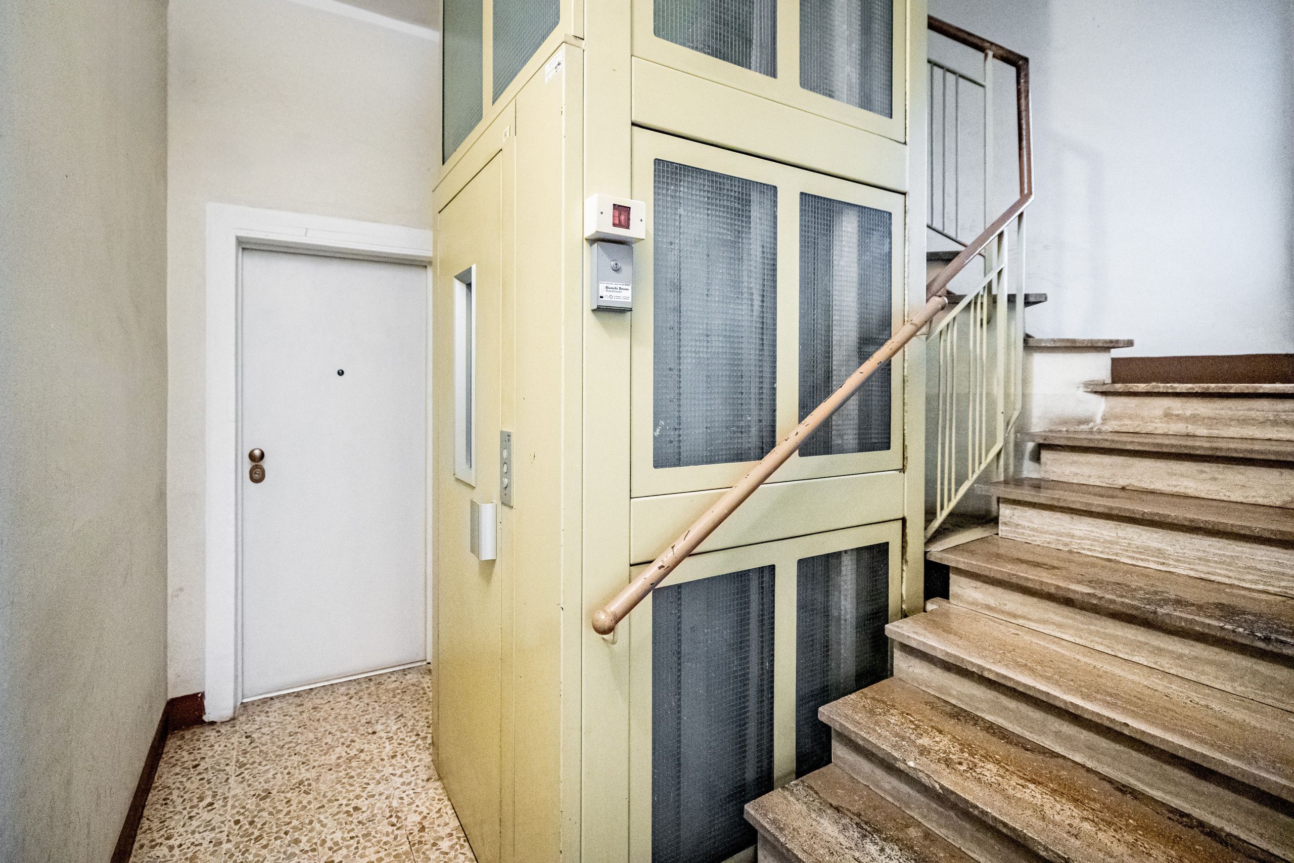 Una escalera con barandilla de madera y paredes color crema.