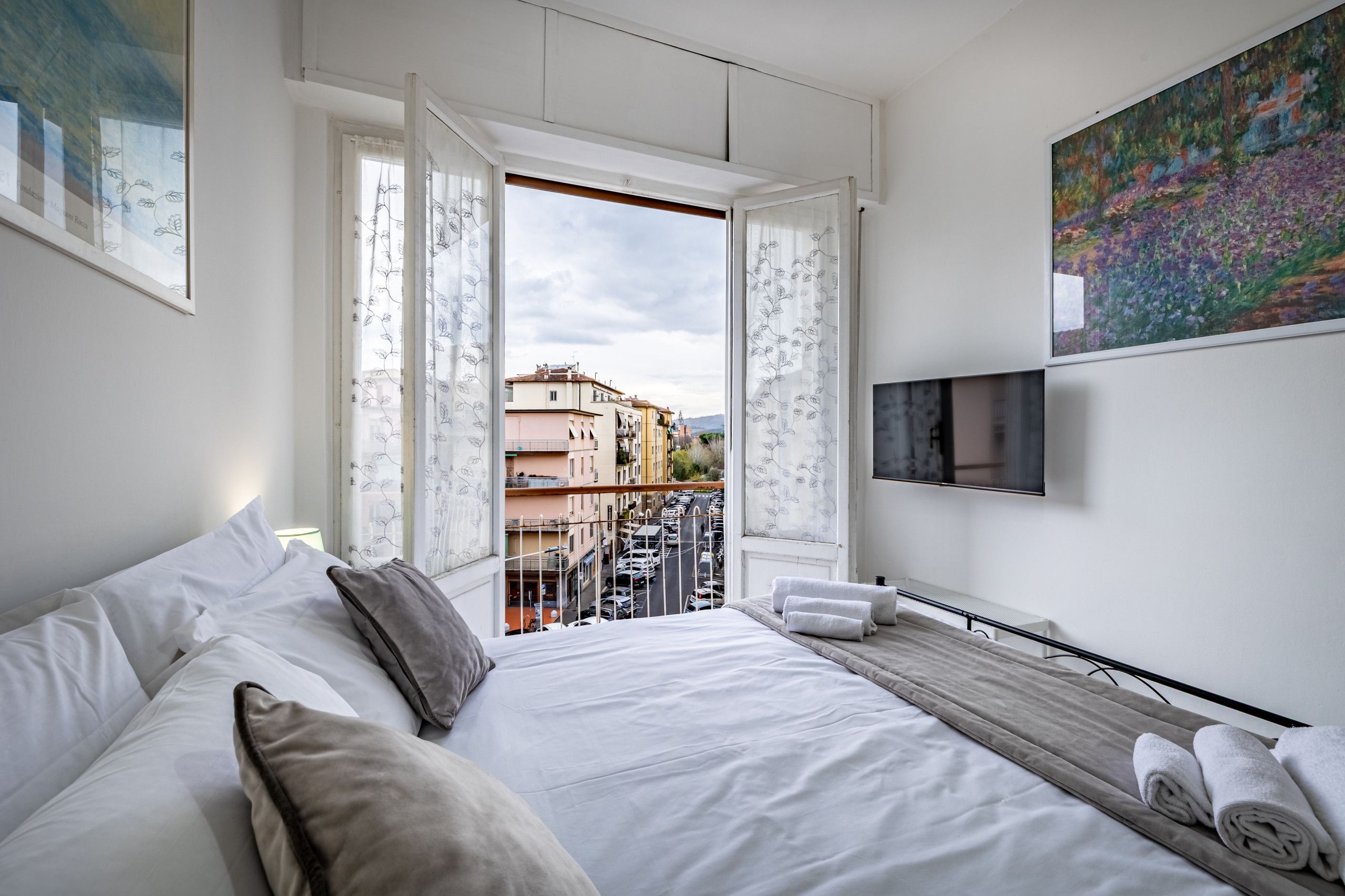 Habitació d'hotel moderna amb llit, televisió i balcó amb vista a la ciutat.