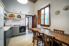 A compact kitchen with a wooden dining table, built-in appliances, and a patterned backsplash. - Mattonaia (Florence)