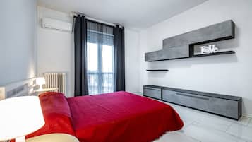 Un dormitorio moderno con cama, mesitas de noche, radiador y ventana con cortinas.