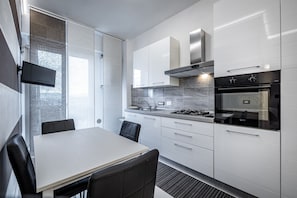 Una cocina moderna con armarios blancos, una estufa a gas y un horno empotrado.