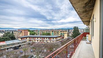 A balcony overlooking a parking area with multiple buildings in the background.