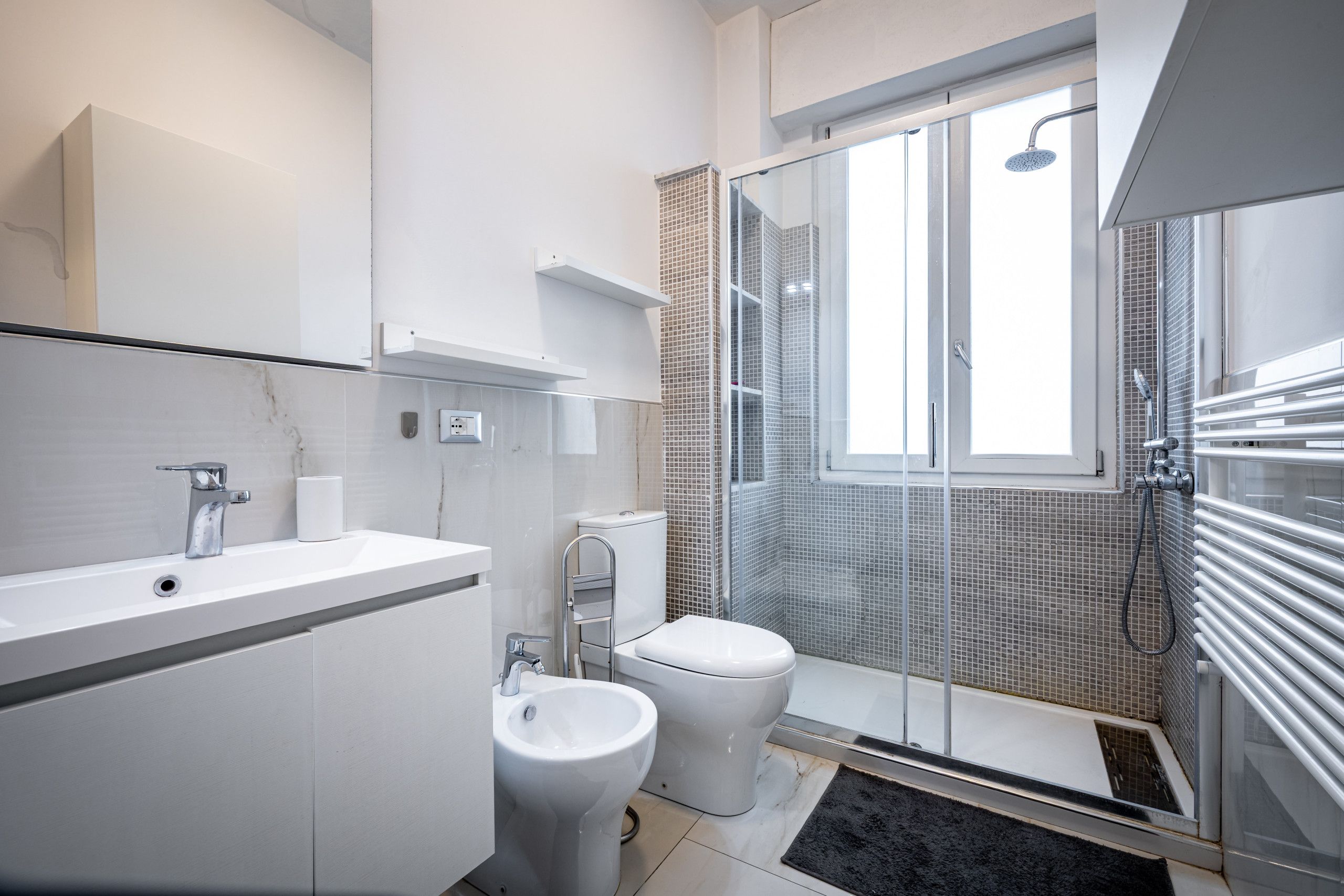A modern bathroom with a shower, toilet, and sink.