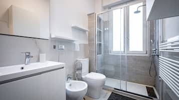 A modern bathroom with a shower, toilet, and sink.
