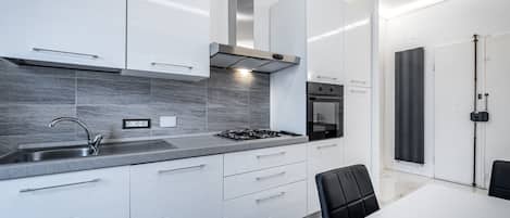 A modern kitchen with white cabinetry, a gas stove, and a built-in oven.