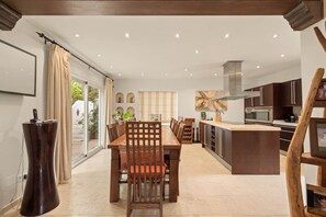 A spacious kitchen with modern appliances, a dining area with a wooden table and chairs, and a large window with curtains. - RDR584 - Mediterranean Villa on Aloha Golf with Pool (Marbella)