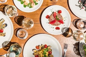 A dining table with multiple plates of food, glasses of water, and cutlery.