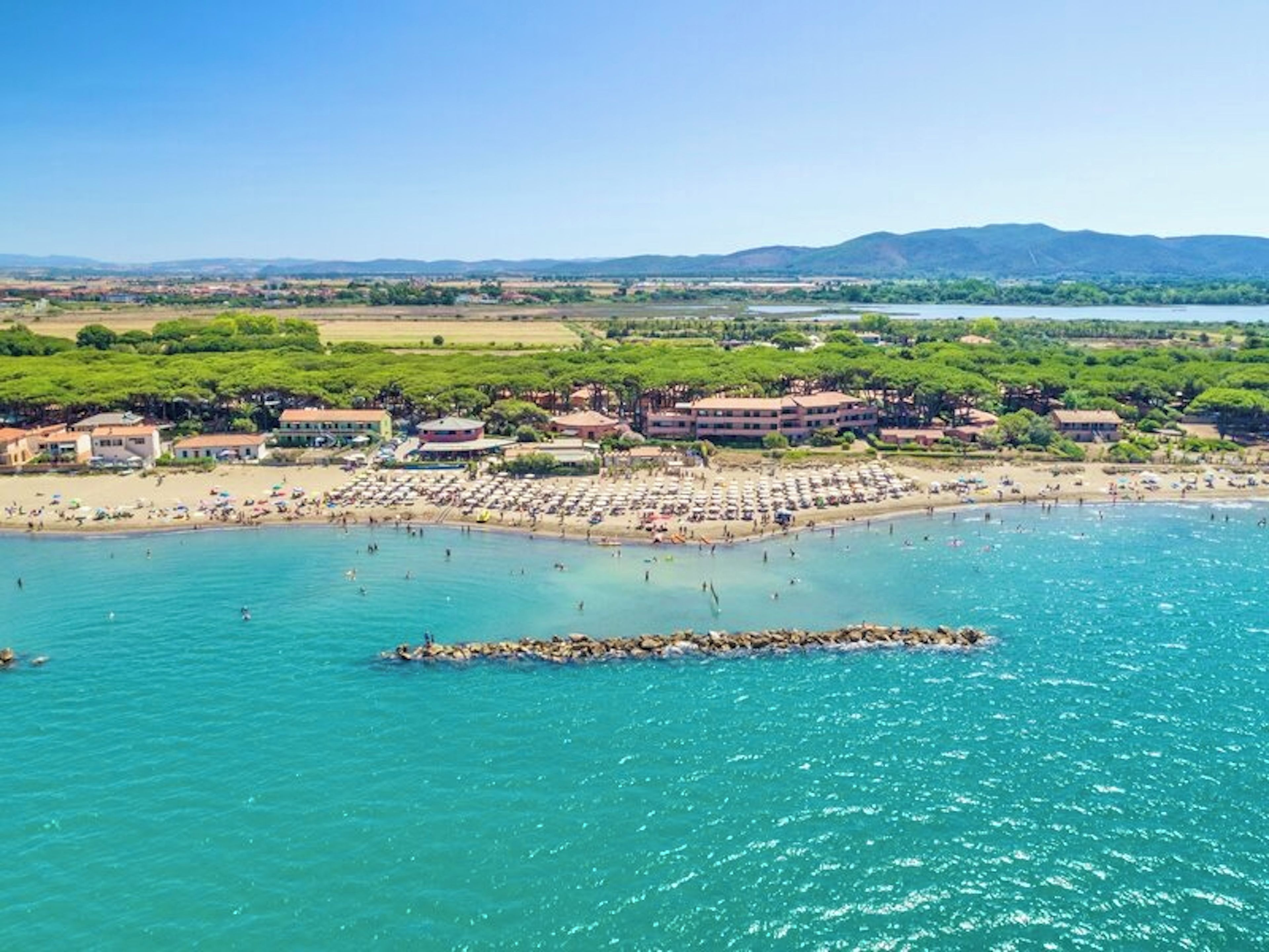 Une station balnéaire dotée d’une plage, de villas et d’une digue rocheuse.