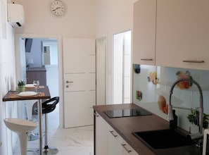 Eine moderne Küche mit Backofen, Spüle und Essbereich inklusive Stuhl und Tisch.