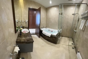 Een badkamer met een douche met glazen wand, een bad en een wastafel met spiegel.