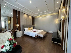 Een moderne hotelkamer met een groot bed, nachtkastjes, een zithoek en een spiegel.