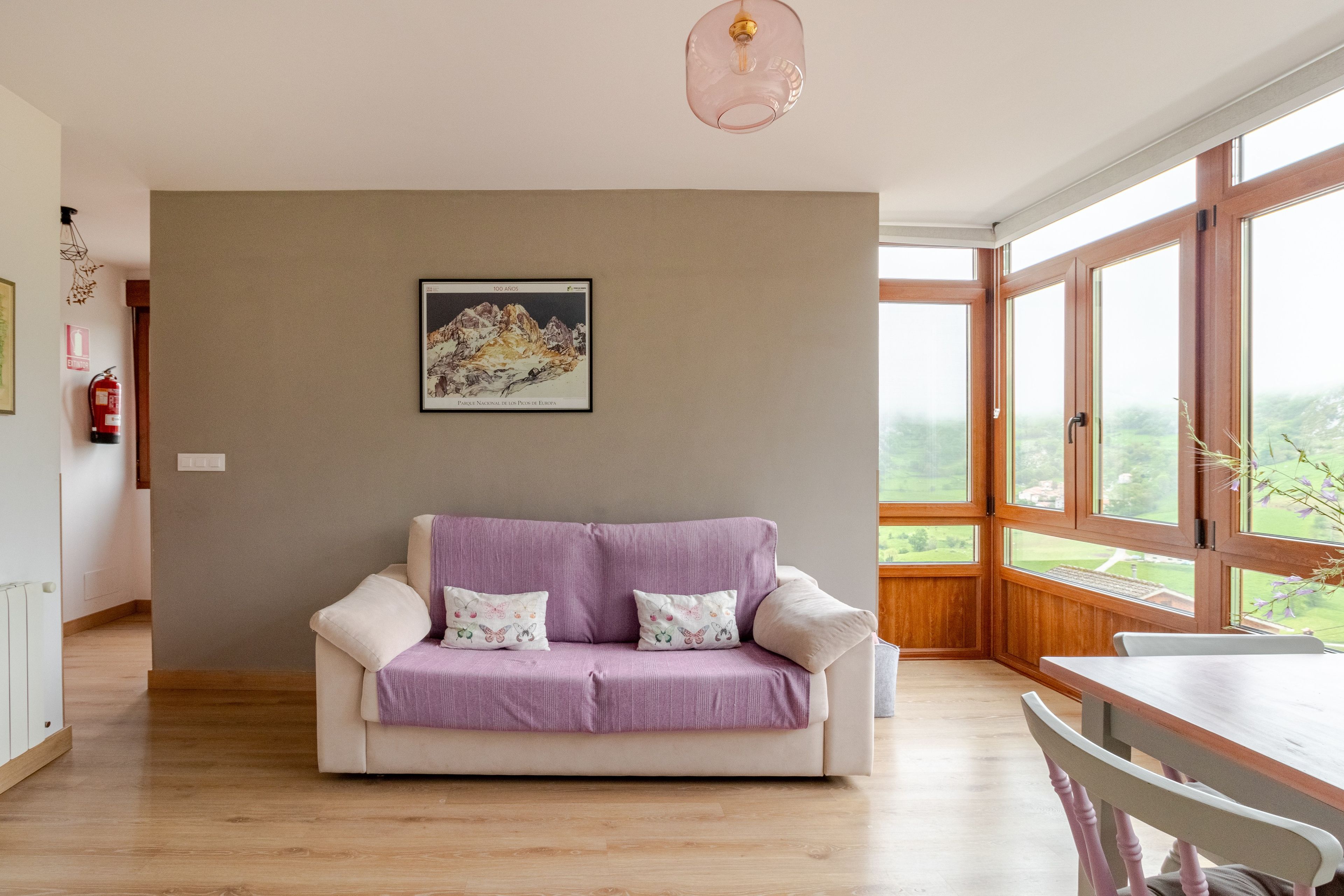 Un salon moderne avec un canapé beige, des coussins violets et un tableau encadré accroché au mur.