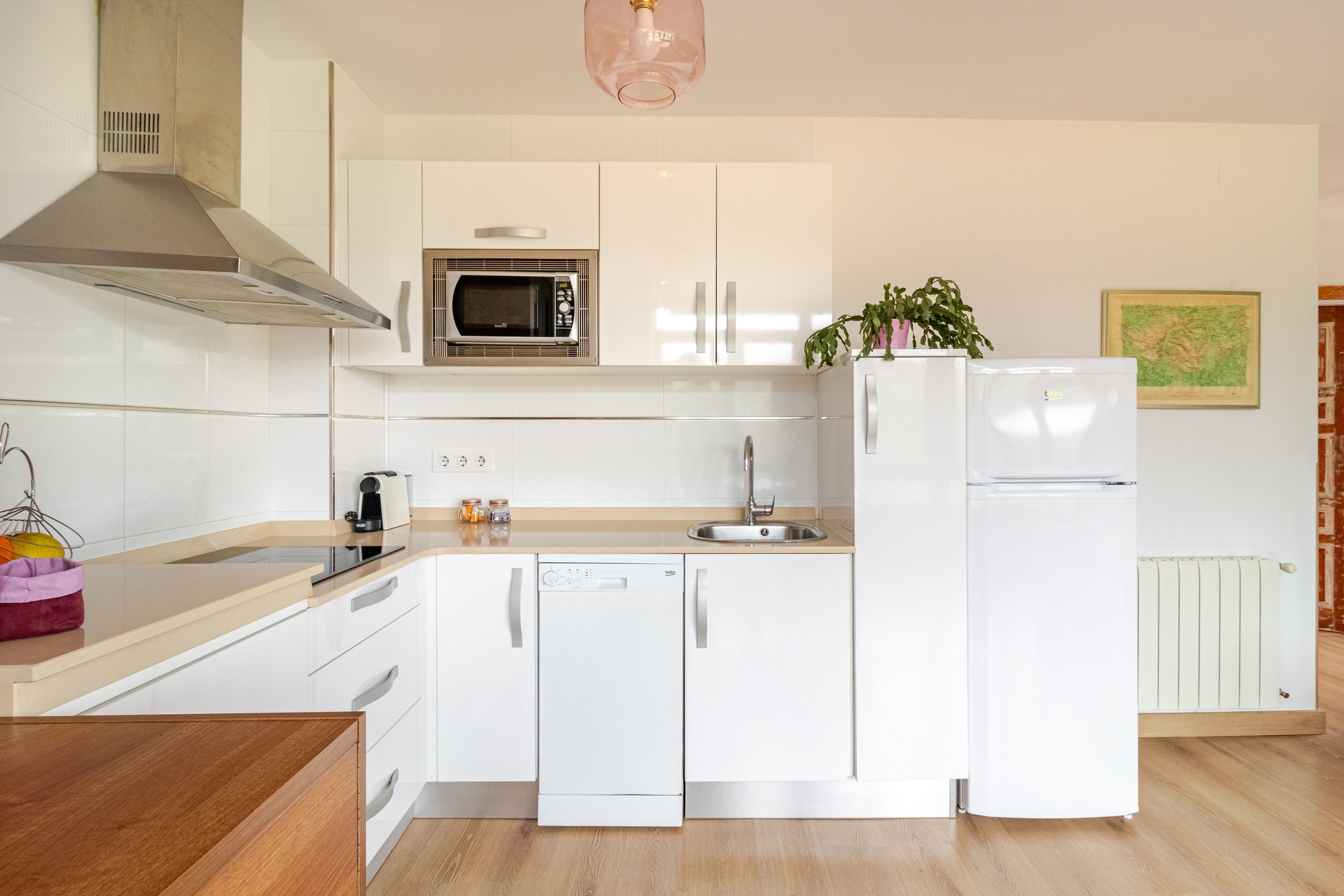 A modern kitchen with white cabinetry, a built-in microwave, a dishwasher, and a refrigerator.
