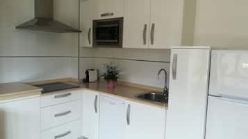Een moderne keuken met witte kasten, een roestvrijstalen spoelbak, een magnetron en een ingebouwde oven.