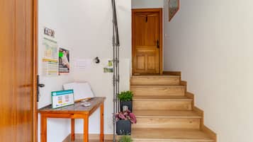Een houten trap die naar een deur leidt, een tafel met een kaart en een QR-code, en een potplant.