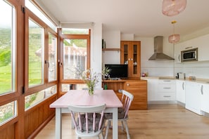 A modern kitchen with wooden cabinets, a dining table with chairs, and a television.