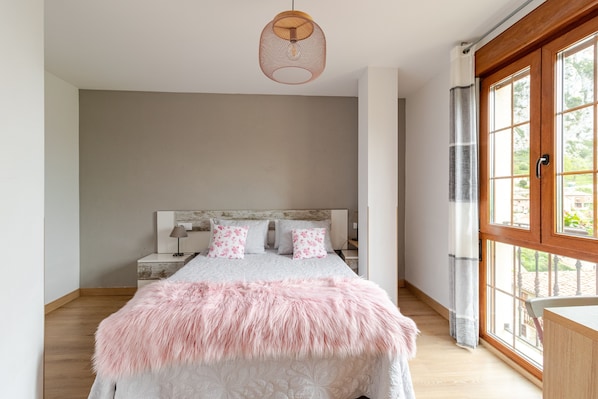 A bedroom with a bed, a nightstand, a lamp, and a window with curtains.