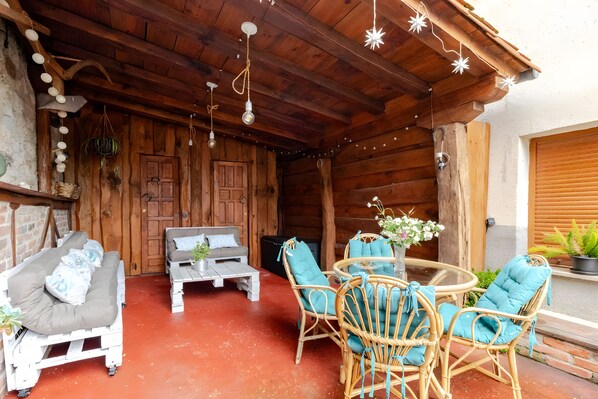 A rustic wooden interior with a sofa, a coffee table, and wicker chairs.