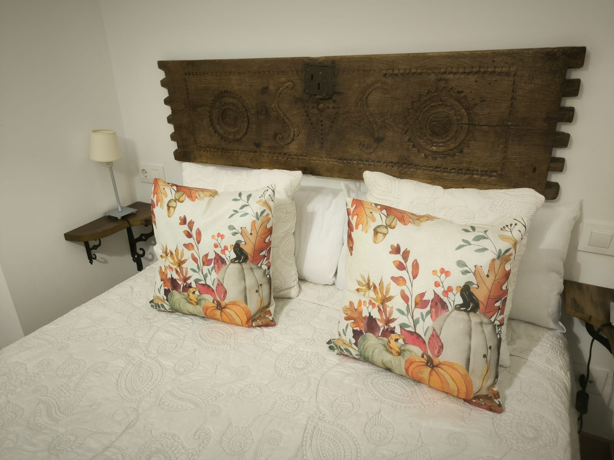 Een bed met twee sierlijke kussens en een houten hoofdbord.
